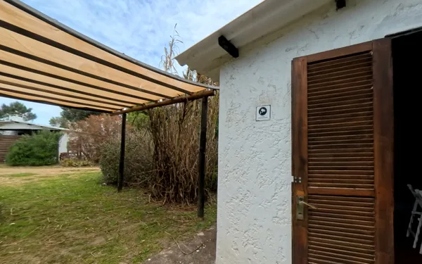 Frente de una cabaña de El Villorrio, con la pérgola y el jardín